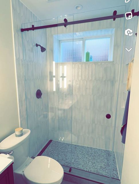 Barn-style sliding glass shower door with black hardware