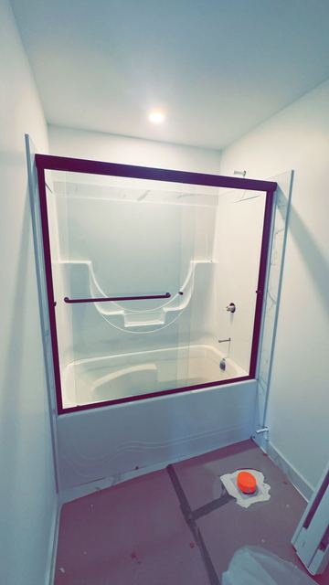 Glass tub enclosure with dark frame